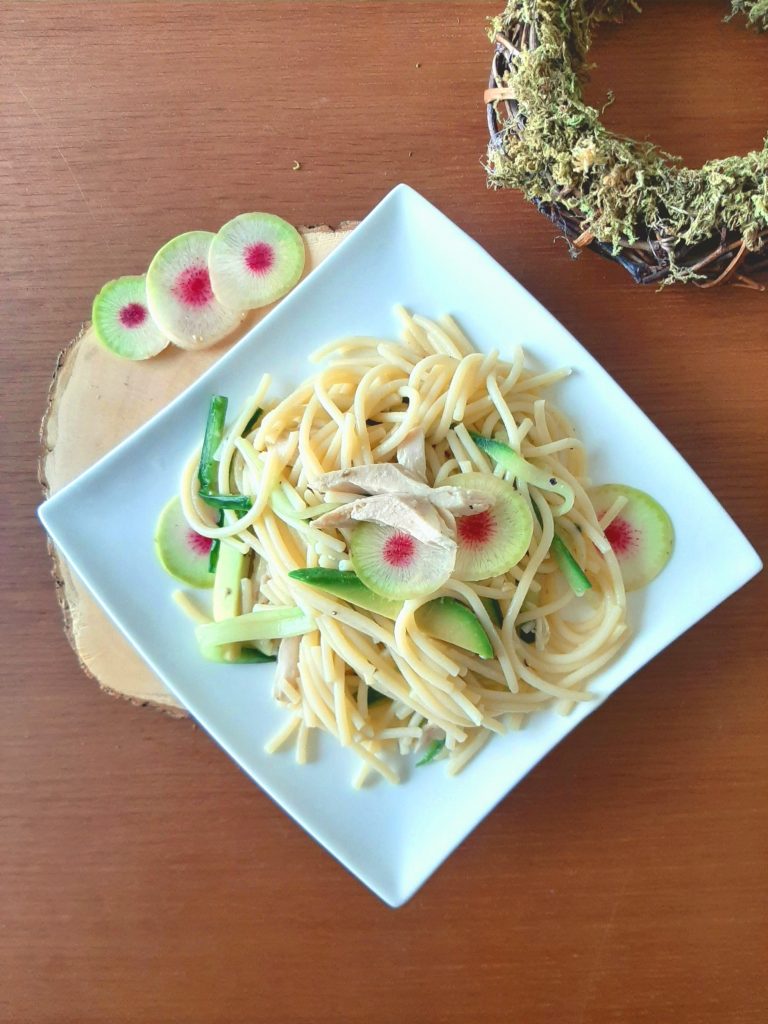 Green pasta with shredded chicken decorated with watermelon radish top view