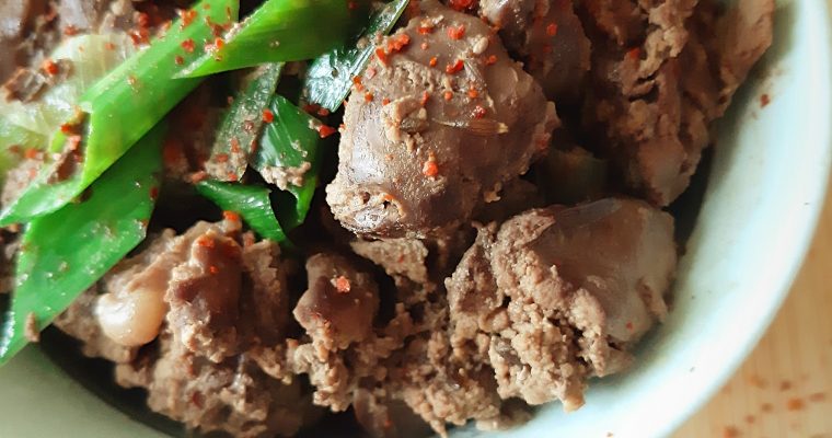 five-spice chicken liver with leeks in a bowl with spices in the background