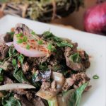 Chicken livers and onions with Swiss chard at an angle with green onion bunch and red onion in the background
