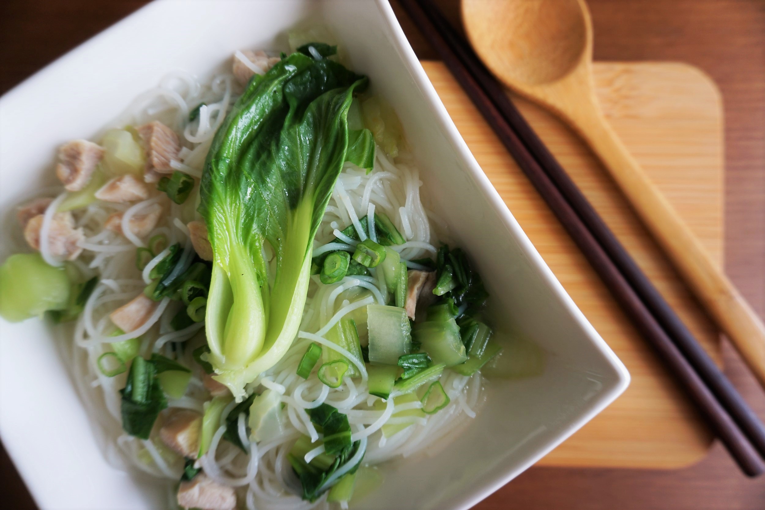 Tender chicken noodle soup close up with chopsticks and spoon