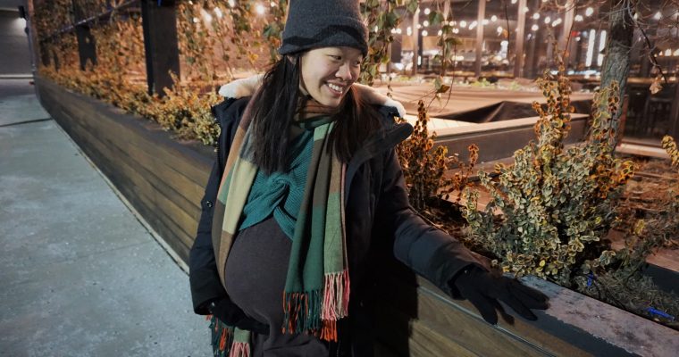 Brenda in third trimester standing in front of restaurant patio with baby bump
