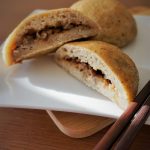 Cross section of gluten free baked bbq pork buns on a plate with chopsticks