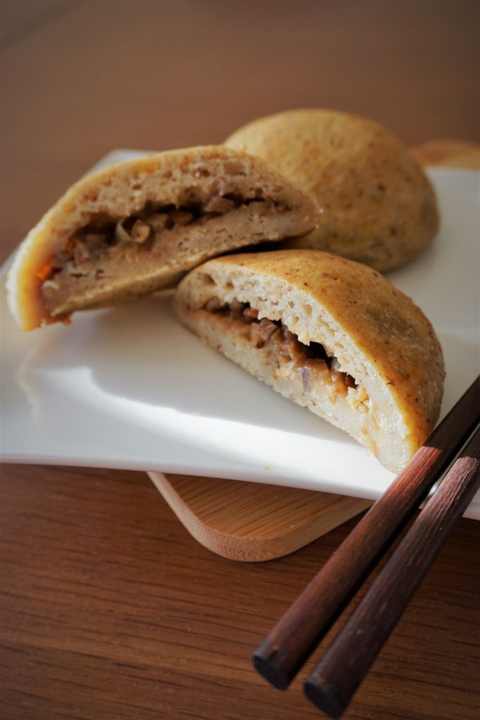 Cross section of gluten free bbq pork bun on a plate with chopsticks 